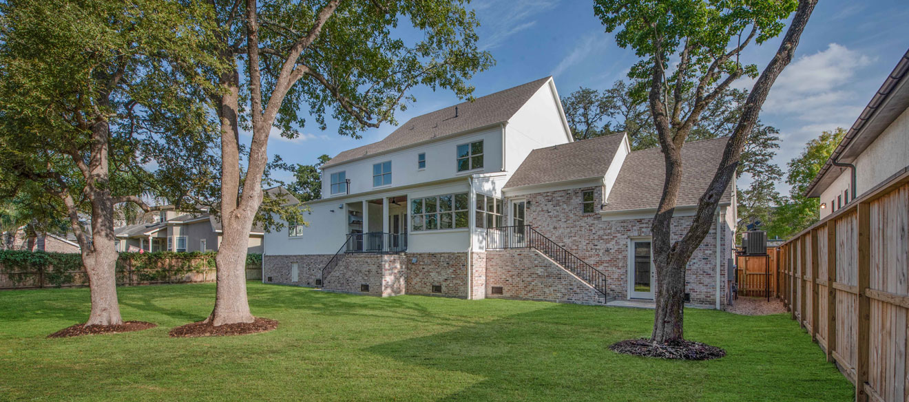 Backyard view of two story home with an enclosed back patio. Home exterior built with brick and plank siding. 