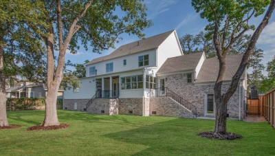 Backyard view of two story home with an enclosed back patio. Home exterior built with brick and plank siding. 