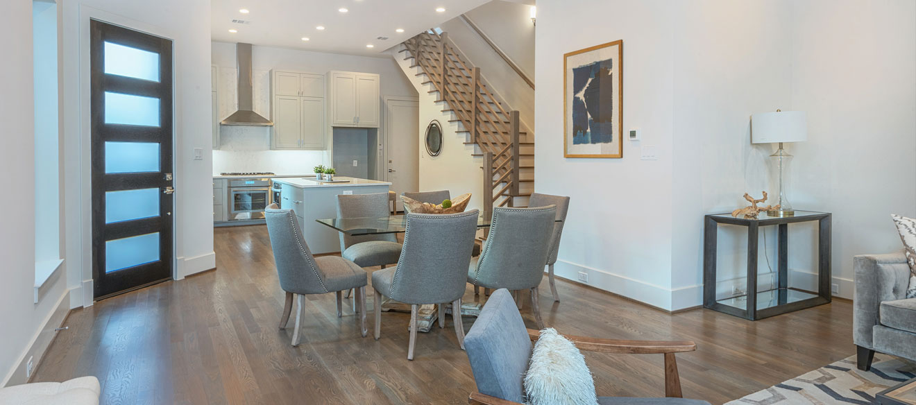 Living room open to kitchen with a staircase entering in the middle. 